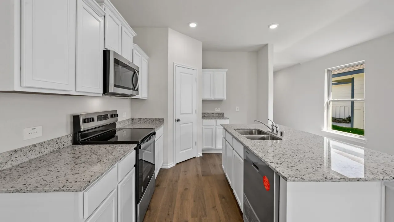 Contemporary kitchen featuring white cabinetry, light-toned countertops, stainless steel appliances, and wood-finish flooring