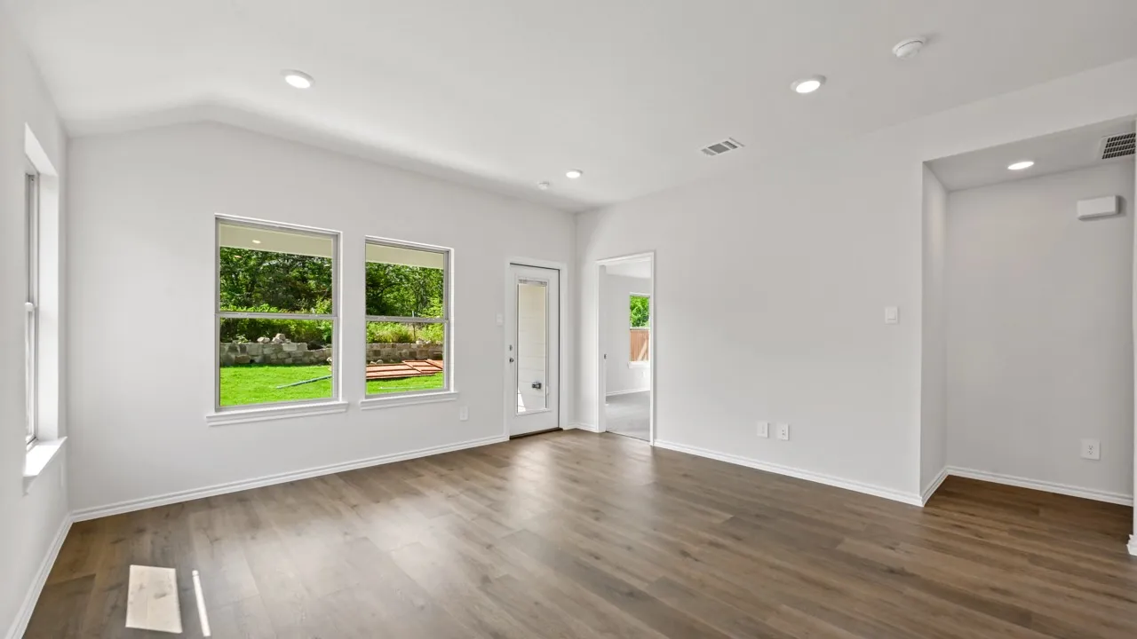Bright interior space featuring vaulted ceilings, recessed lighting, wood-finish flooring, multiple windows, and a glass-paneled exterior door