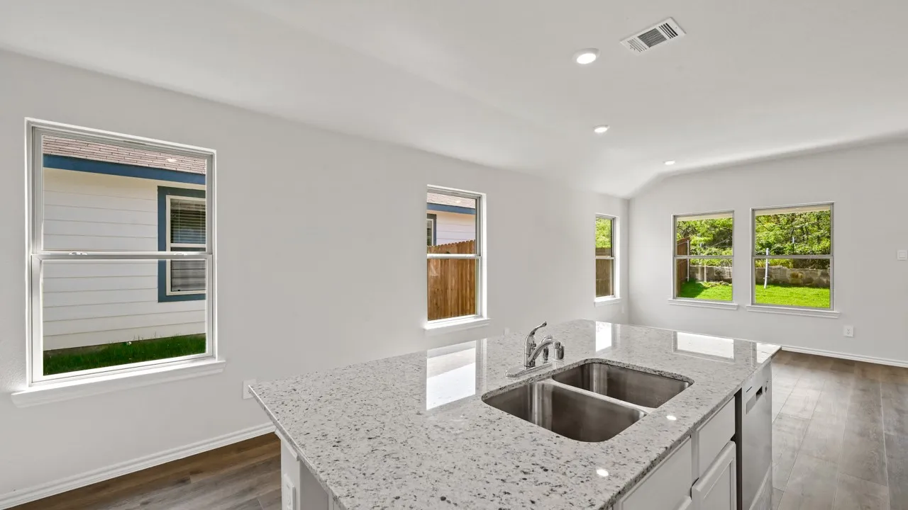 Kitchen island featuring a dual stainless steel sink, chrome faucet, and speckled countertop