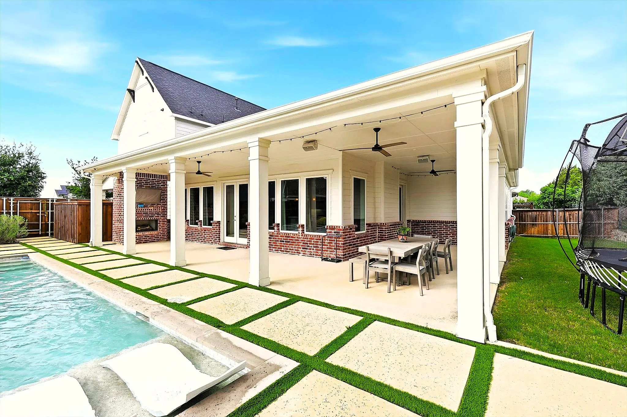 Covered wrap around patio with fireplace, gas grill connection, TV and integrated stereo speakers overlooking the pool