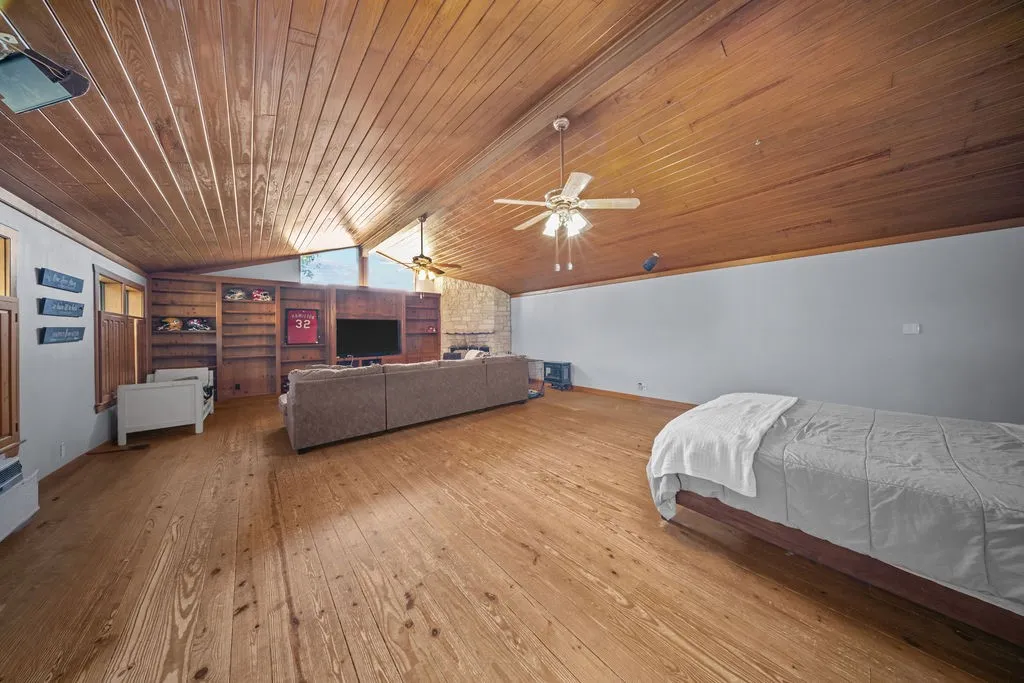 Spacious living area featuring wooden plank flooring and an angled wooden plank ceiling with exposed beams