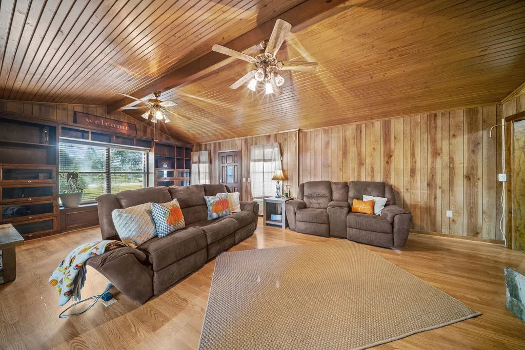 The living area features wood paneling on the walls and ceiling, along with light wood flooring