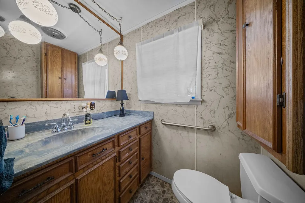 Bathroom featuring a vanity with a countertop sink, a window with white blinds, and overhead lighting fixtures