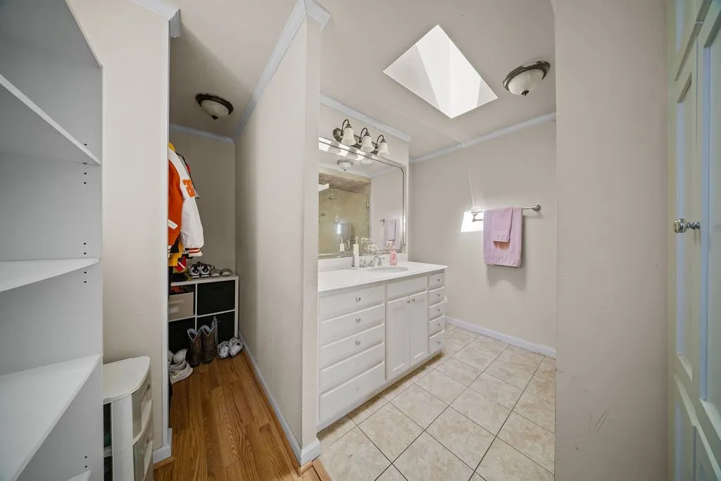 Bathroom featuring a vanity with a white countertop and base, a mirror, and tiled flooring