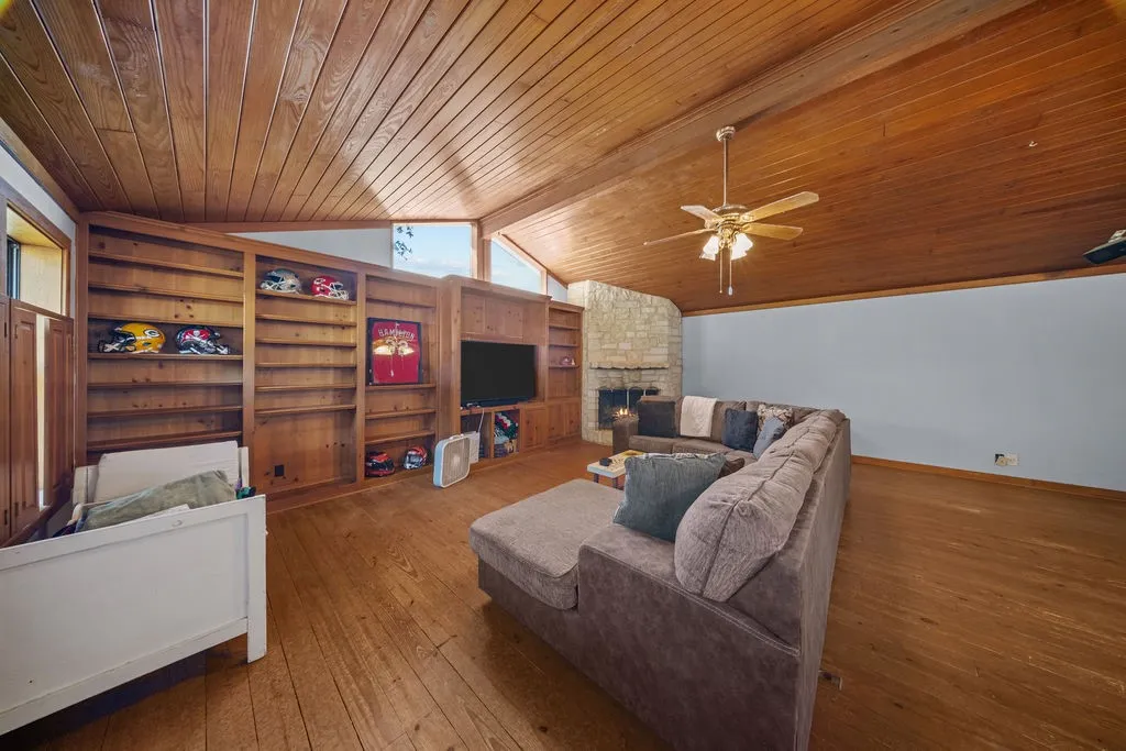 Living area featuring a vaulted wood-paneled ceiling, wood flooring, and built-in wooden shelving