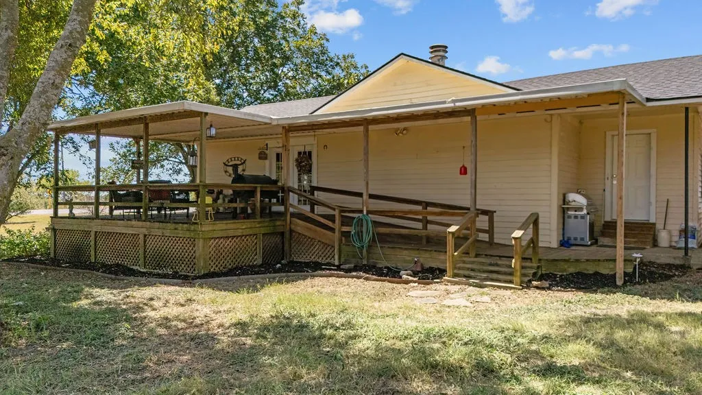 The property features an extensive covered porch and an elevated deck with a wooden railing
