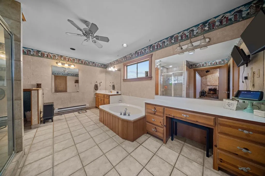 Bathroom featuring a jetted tub, a separate shower enclosure, and a vanity with a large mirror