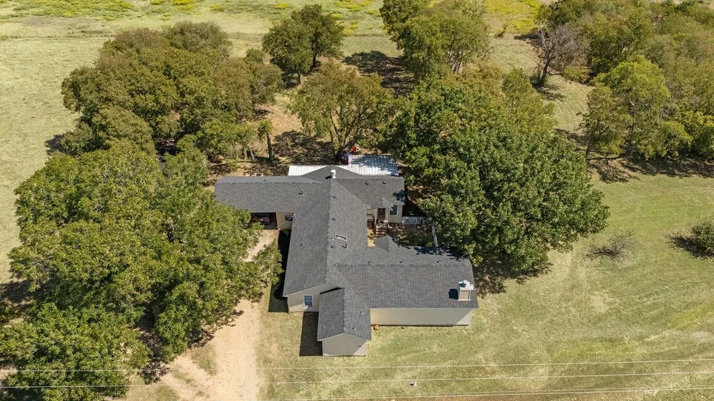 The property features an L-shaped roofline, a dark shingle roof, and light-colored siding