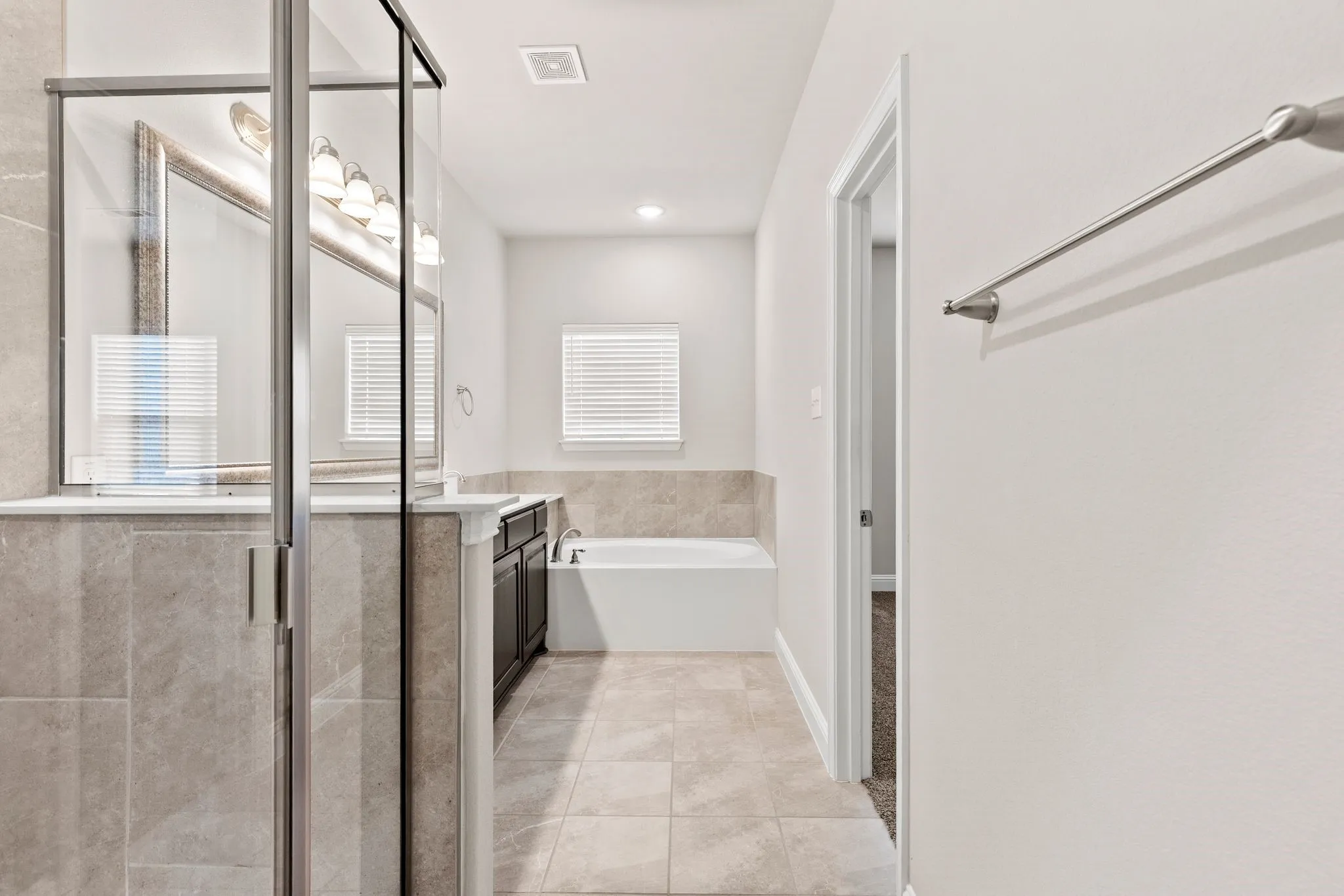 Master Bathroom featuring a glass-enclosed shower, a vanity with a large mirror and lighting, and a separate bathtub