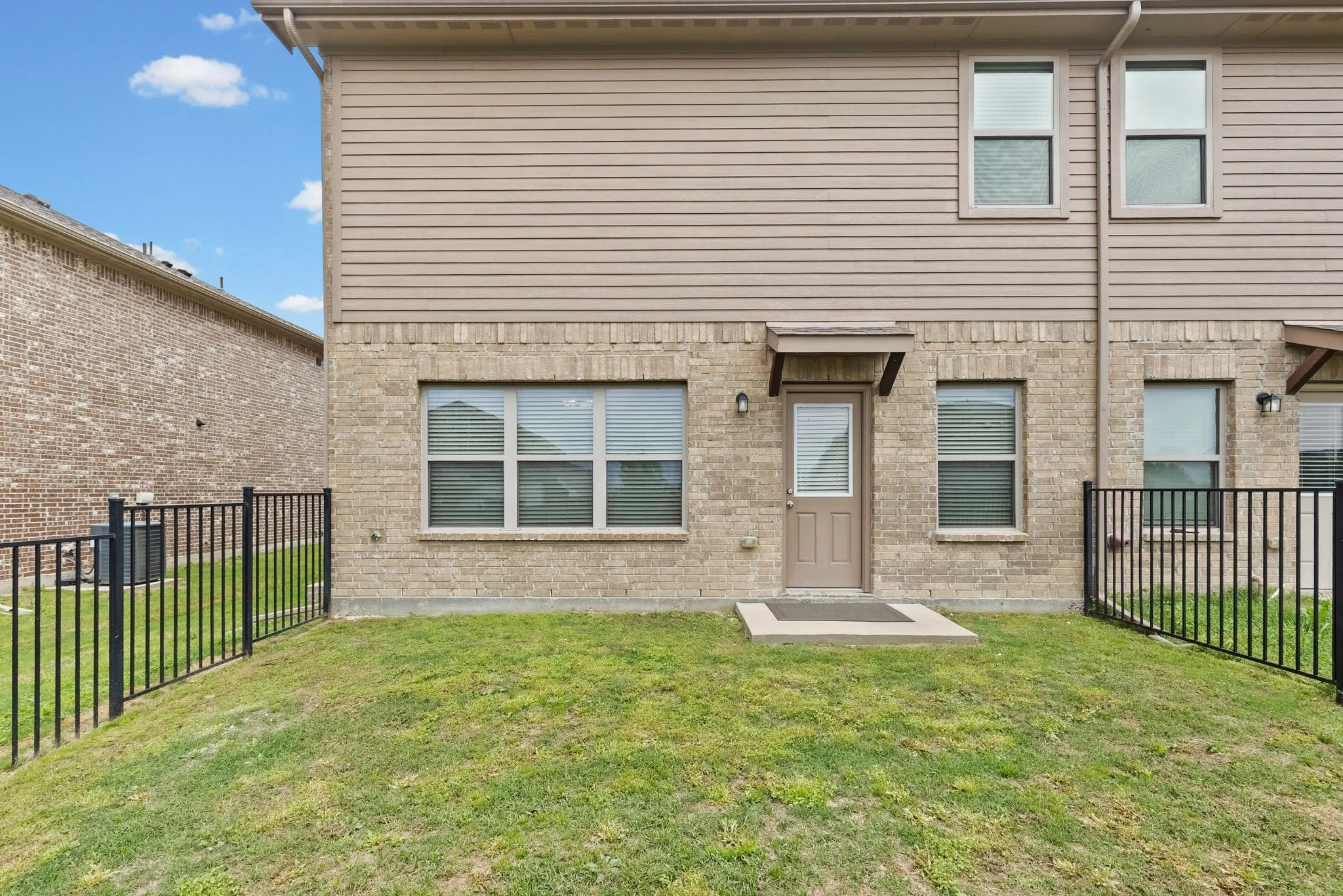 The property features a well-maintained lawn, a brick and siding exterior, and a fenced yard
