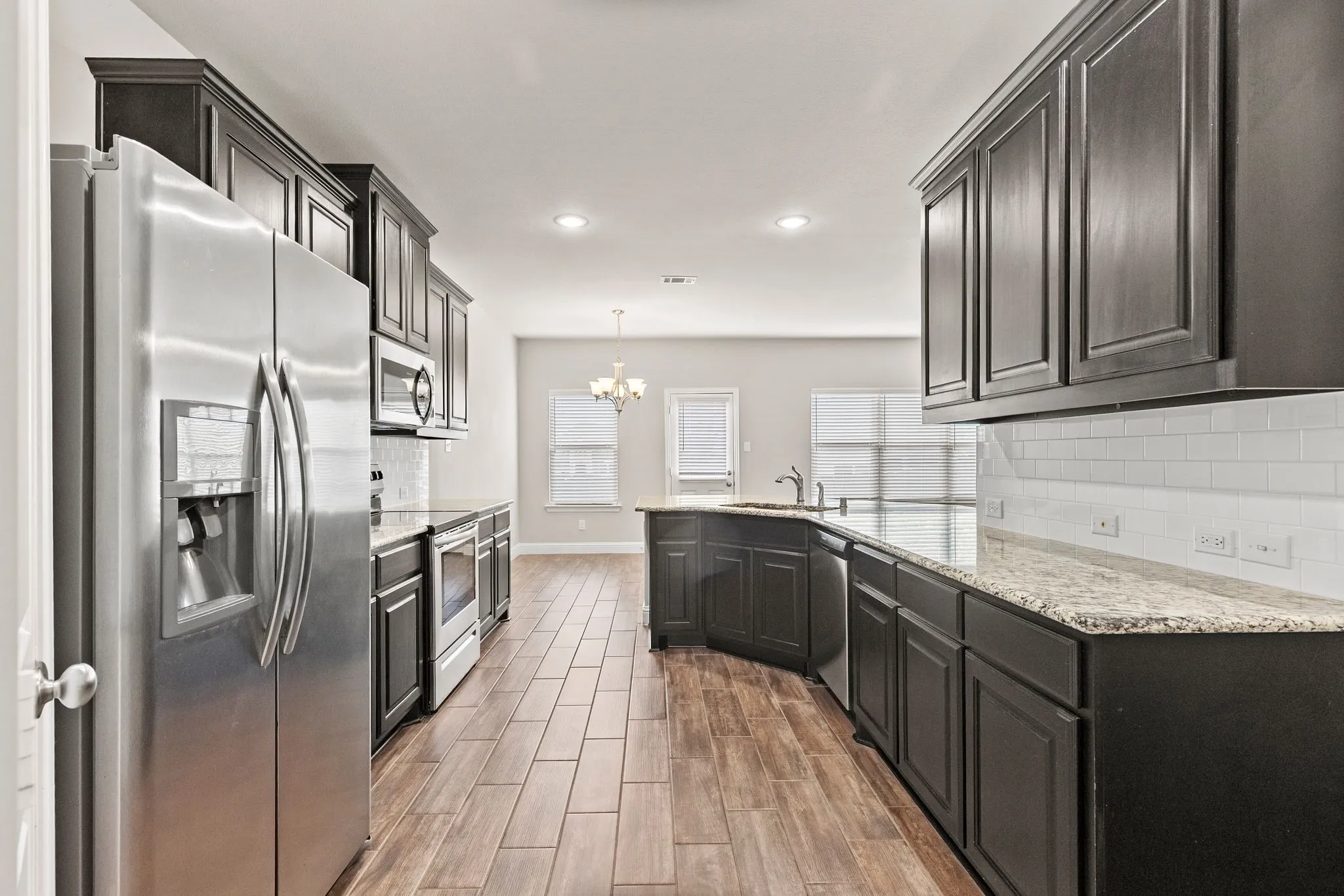 The property features a kitchen with dark cabinetry, stainless steel appliances, and light-colored granite countertops