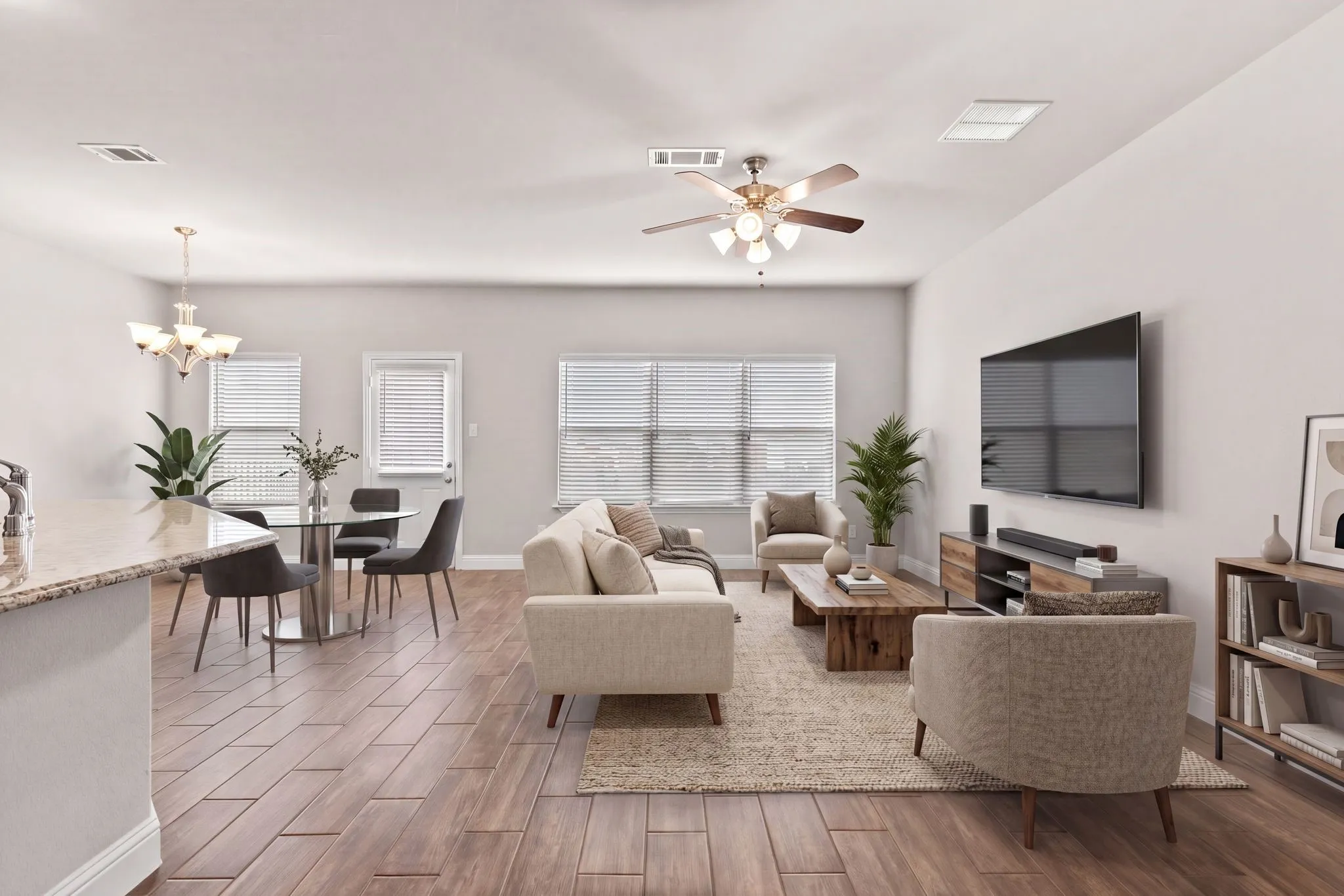 This open-concept living area features wood-look tile flooring, light-colored walls, and a ceiling fan with integrated lighting