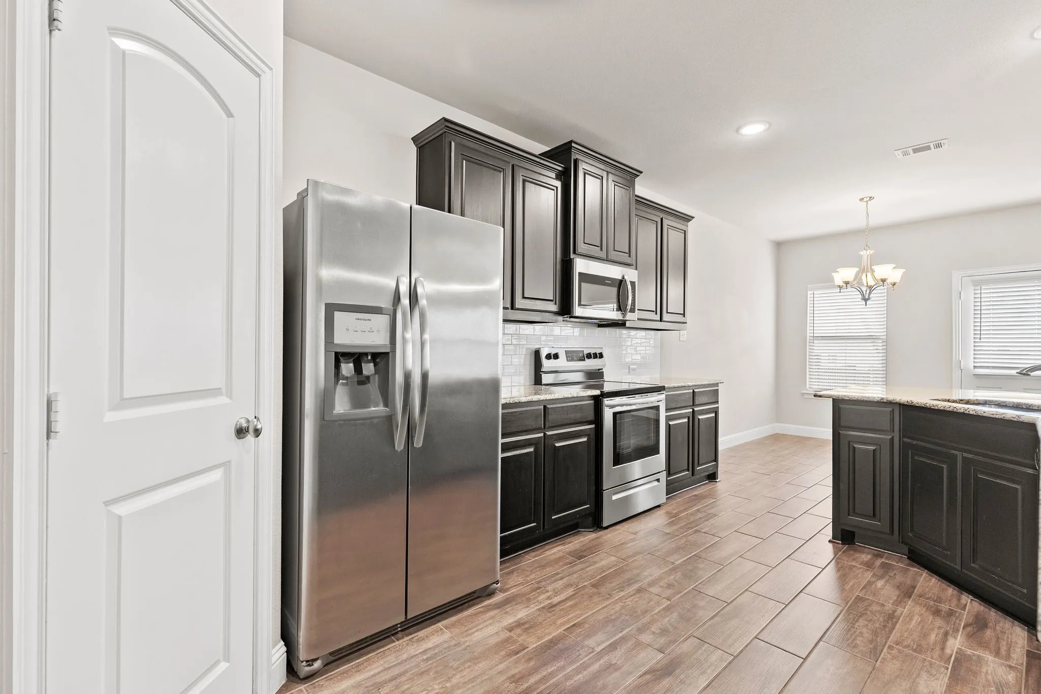 The kitchen features stainless steel appliances, dark wood cabinetry, and granite countertops