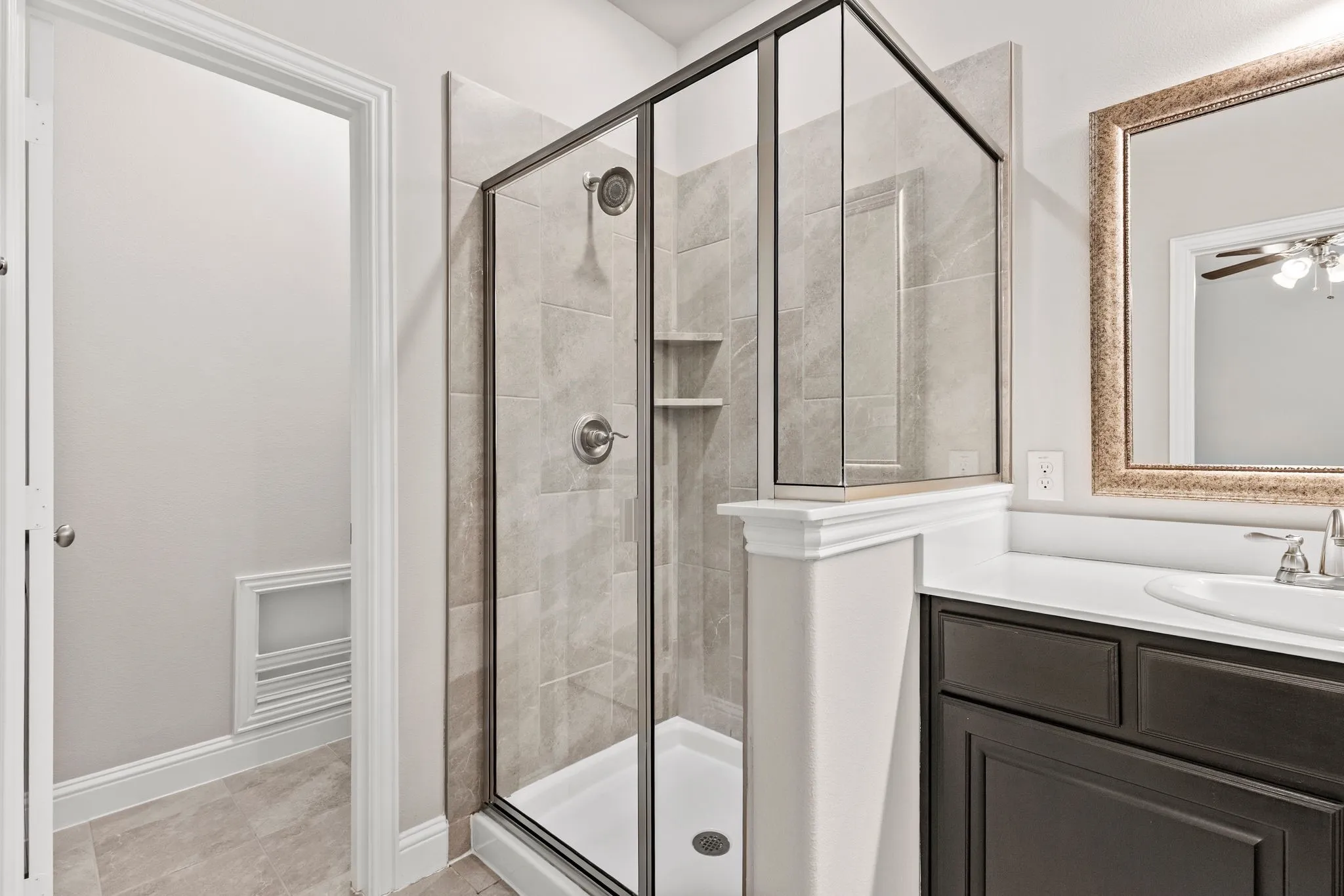 Master bathroom features a glass-enclosed shower with tiled walls and a built-in shelf in toilet area