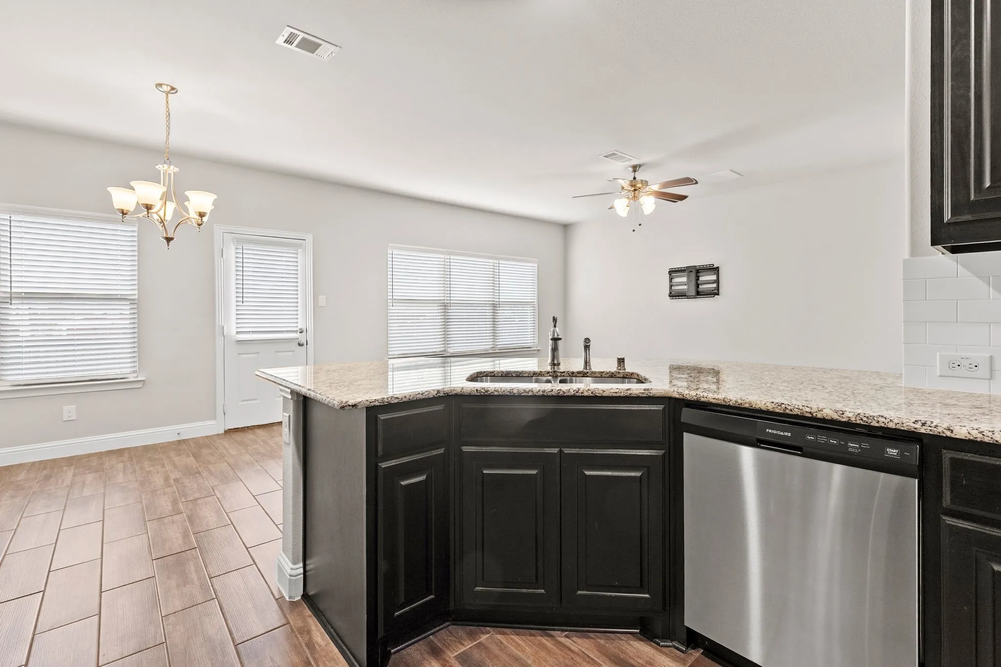The kitchen features dark cabinetry, granite countertops, a stainless steel dishwasher, and a sink with a gooseneck faucet