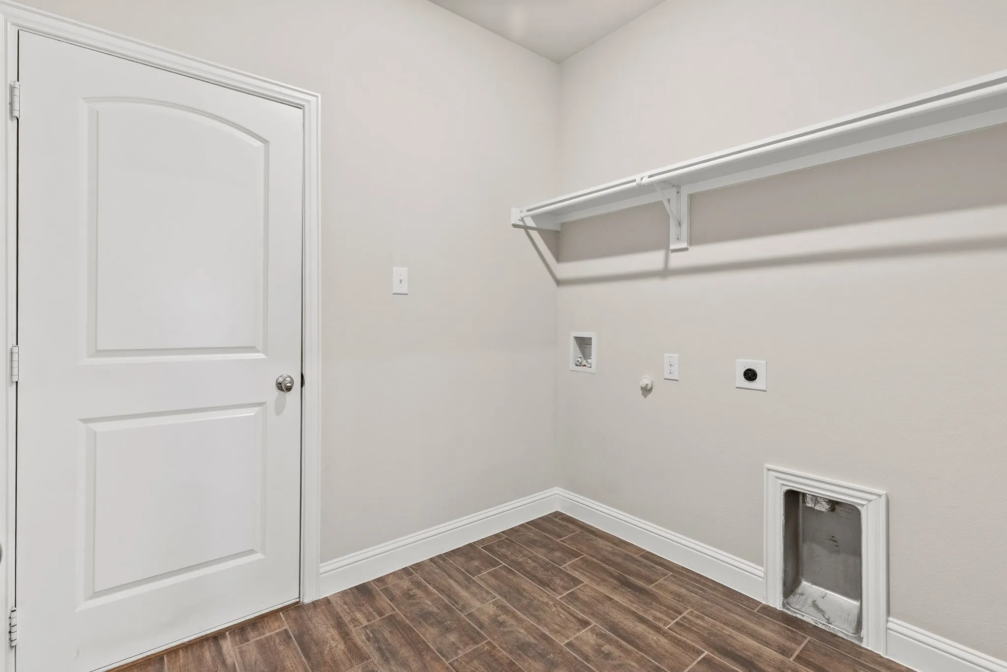 Utility space featuring wood-look tile flooring, white shelving, and a white paneled door