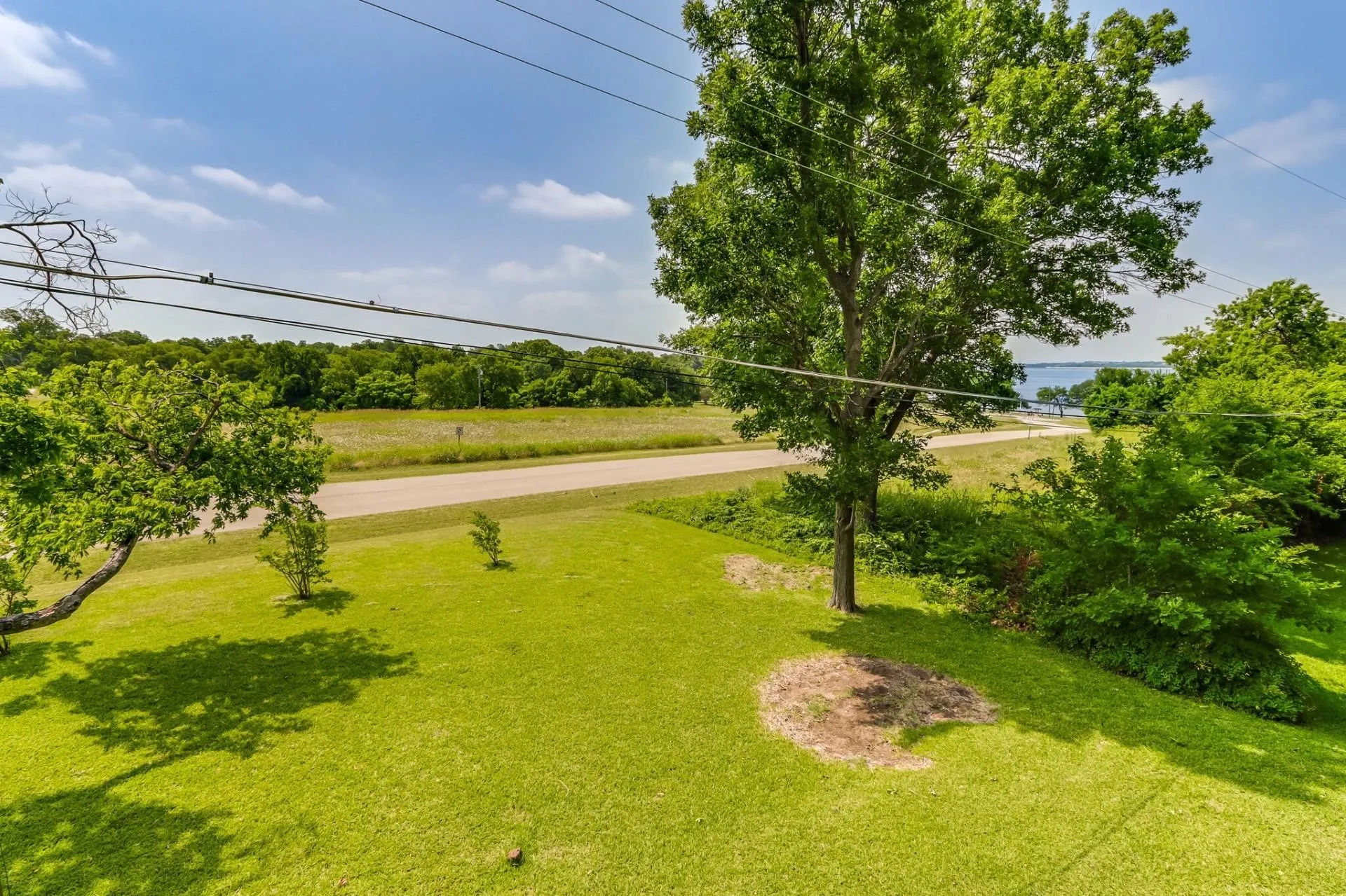 Expansive green lawn with mature trees and a distant body of water