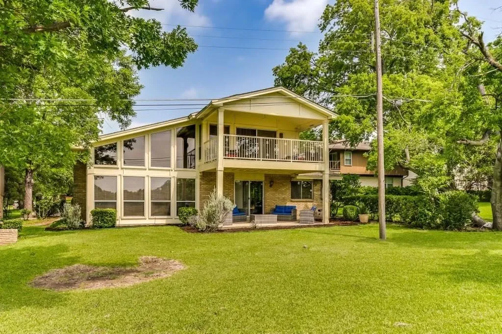 Two-story exterior with expansive window walls, stone accents, and an upper-level balcony