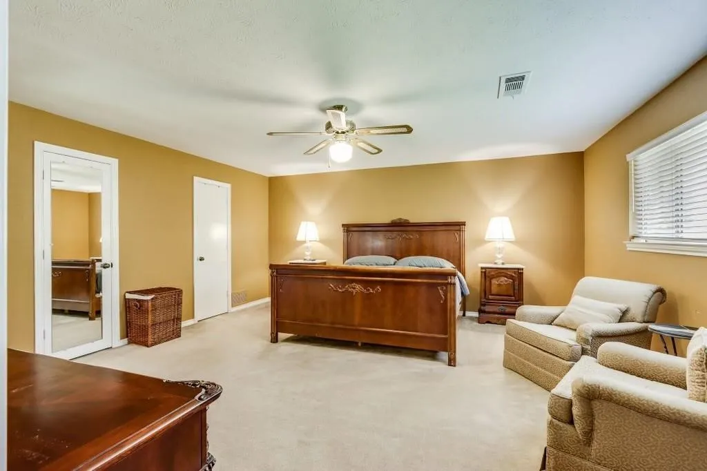 Carpeted room featuring a ceiling fan with integrated lighting, window with blinds, and two solid-core interior doors