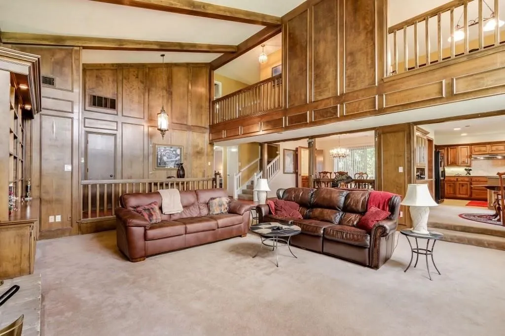 Two-story living area featuring extensive wood paneling and exposed ceiling beams