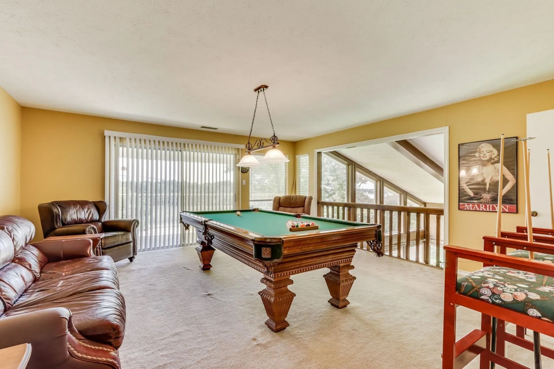 Recreation area featuring a billiard table with an overhead chandelier, neutral carpet flooring, and a sliding glass door