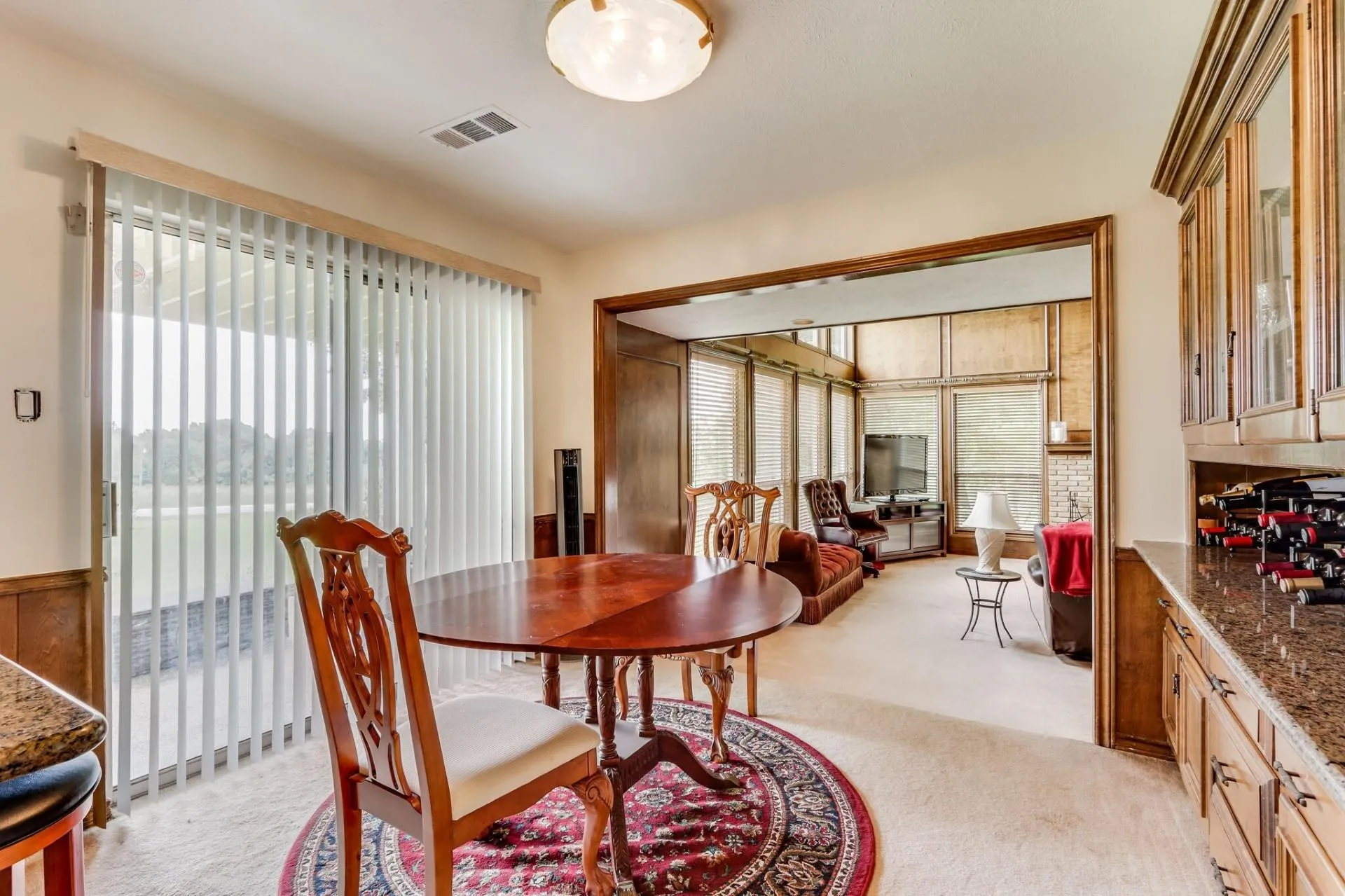 Dining area featuring wood-finish paneling and sliding glass doors with vertical blinds