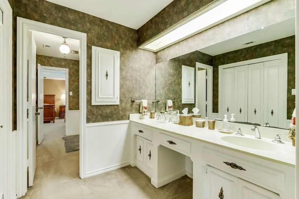 Bathroom featuring a dual vanity with integrated sinks, a large wall-mounted mirror, and a built-in wall cabinet