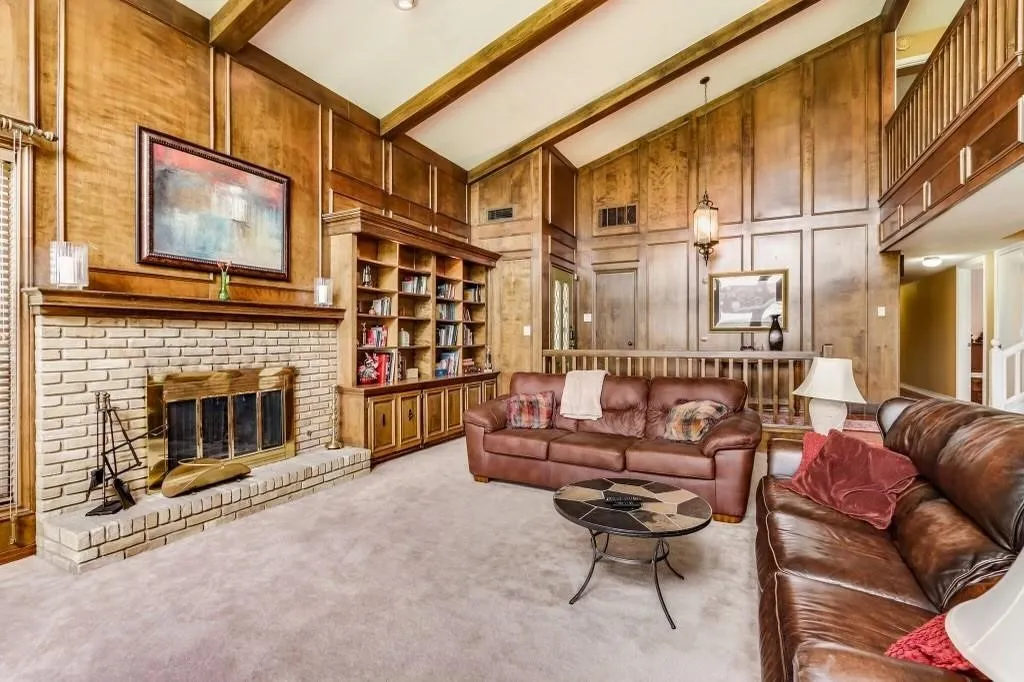 Two-story living area featuring a vaulted ceiling with exposed wood beams