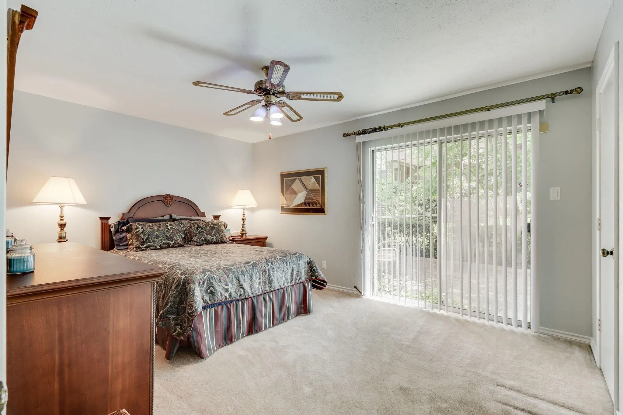 Spacious room featuring light-colored carpet flooring, a ceiling fan with integrated lighting, and light gray wall paint