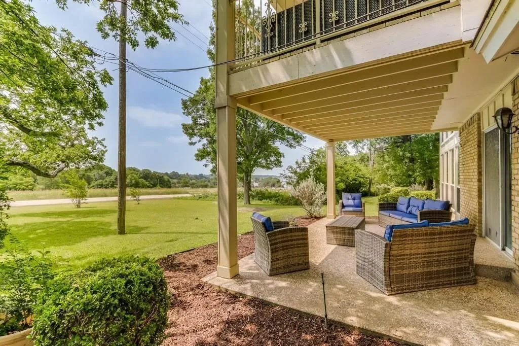 Covered patio featuring a concrete surface, exposed aggregate finish, and an overhead balcony with ironwork railing