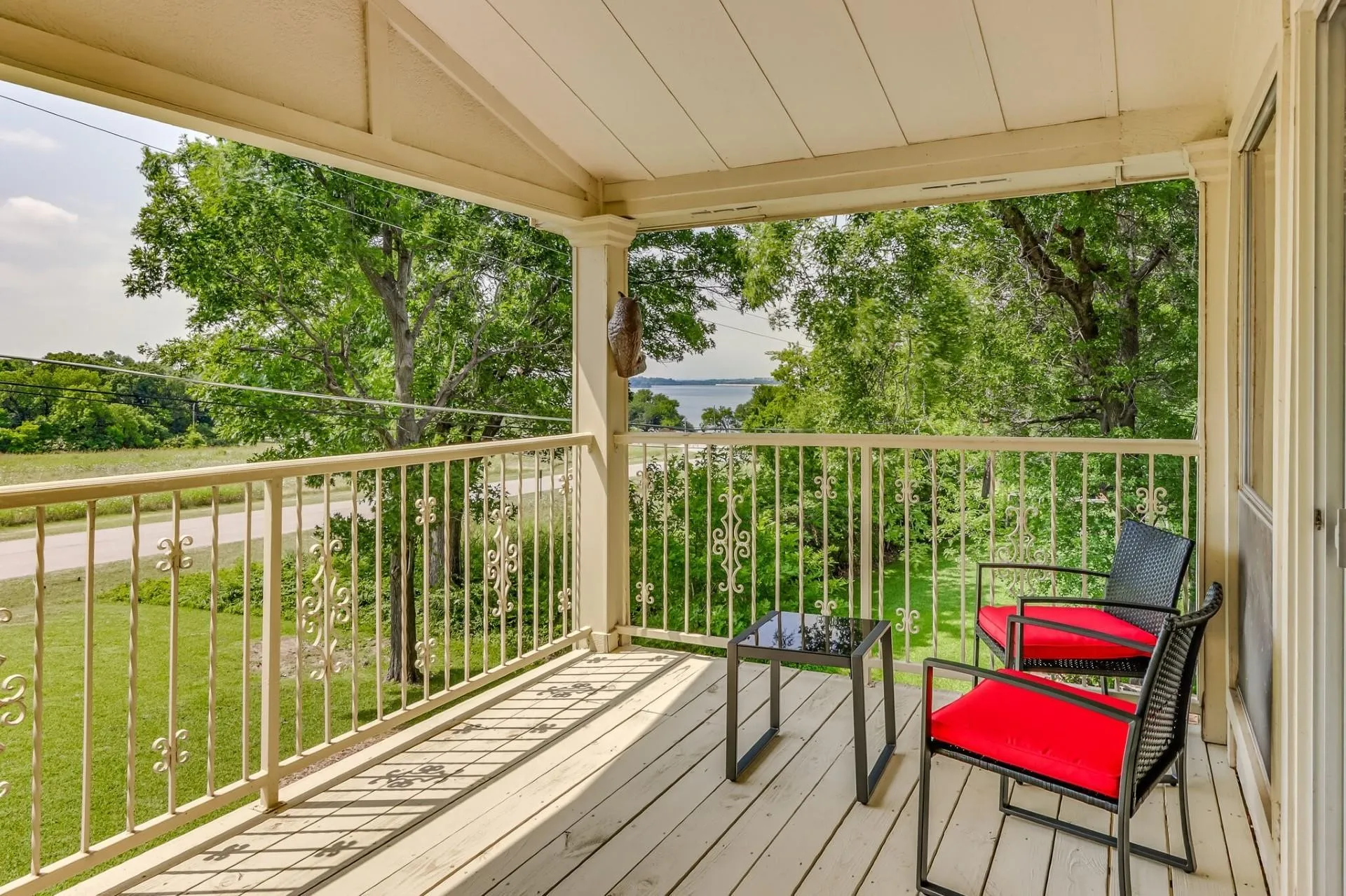 Covered balcony with painted wood-finish flooring, featuring a decorative metal railing and white columns