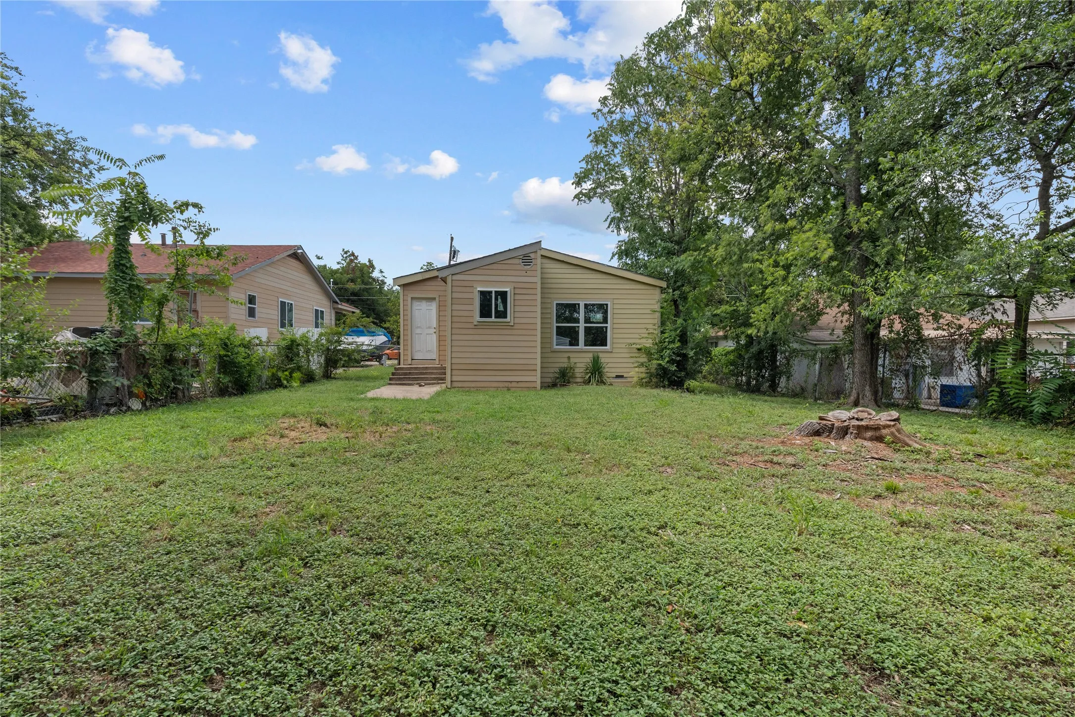 Expansive lawn area with a small, detached structure featuring tan siding and a white entry door