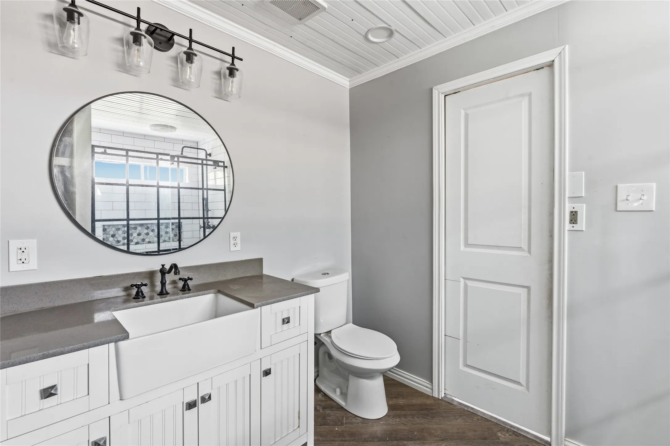 Bathroom vanity featuring a farmhouse sink, dark countertop, and matte black faucet