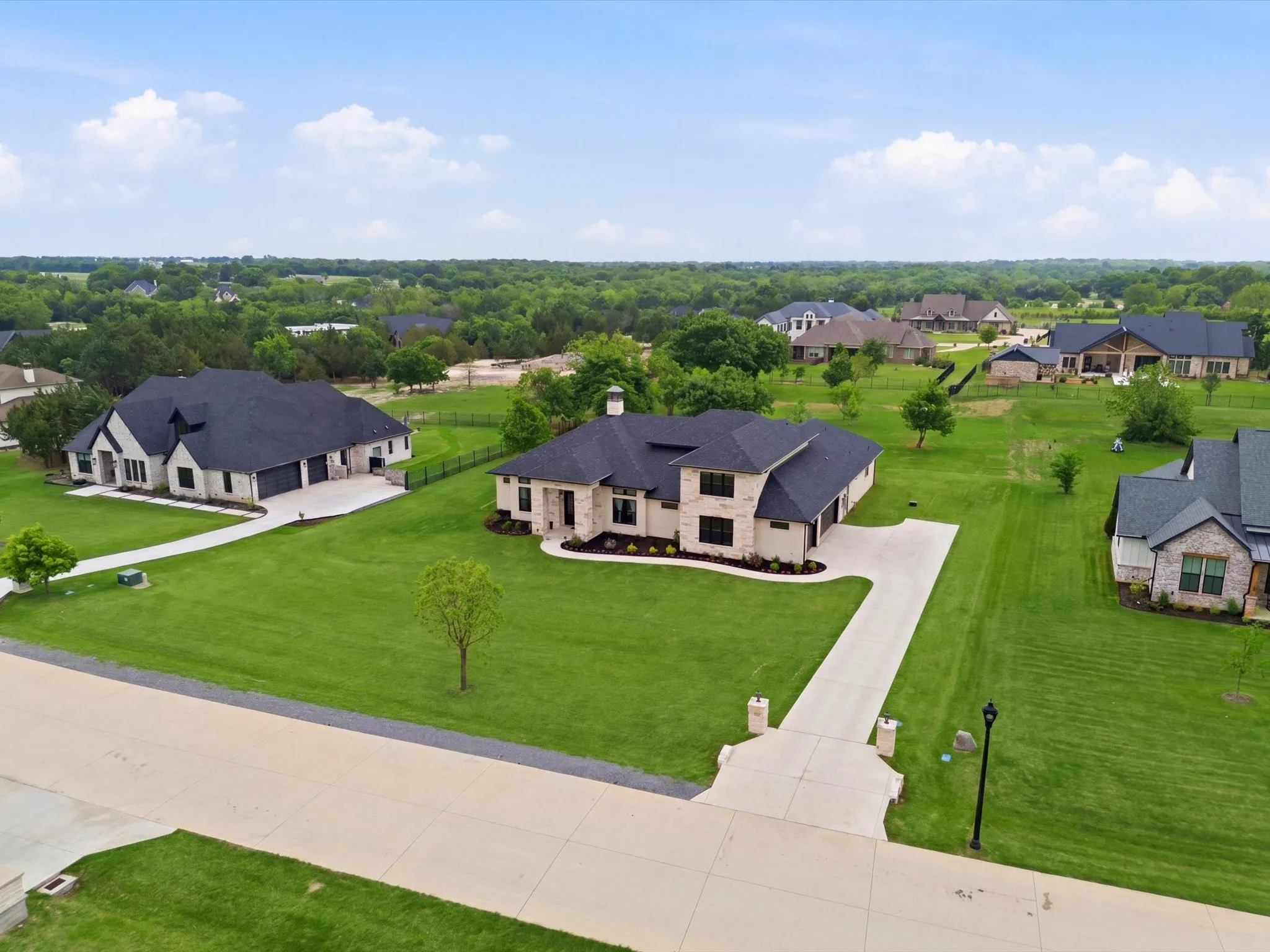 Stone exterior residence with a dark shingle roof and an expansive lawn
