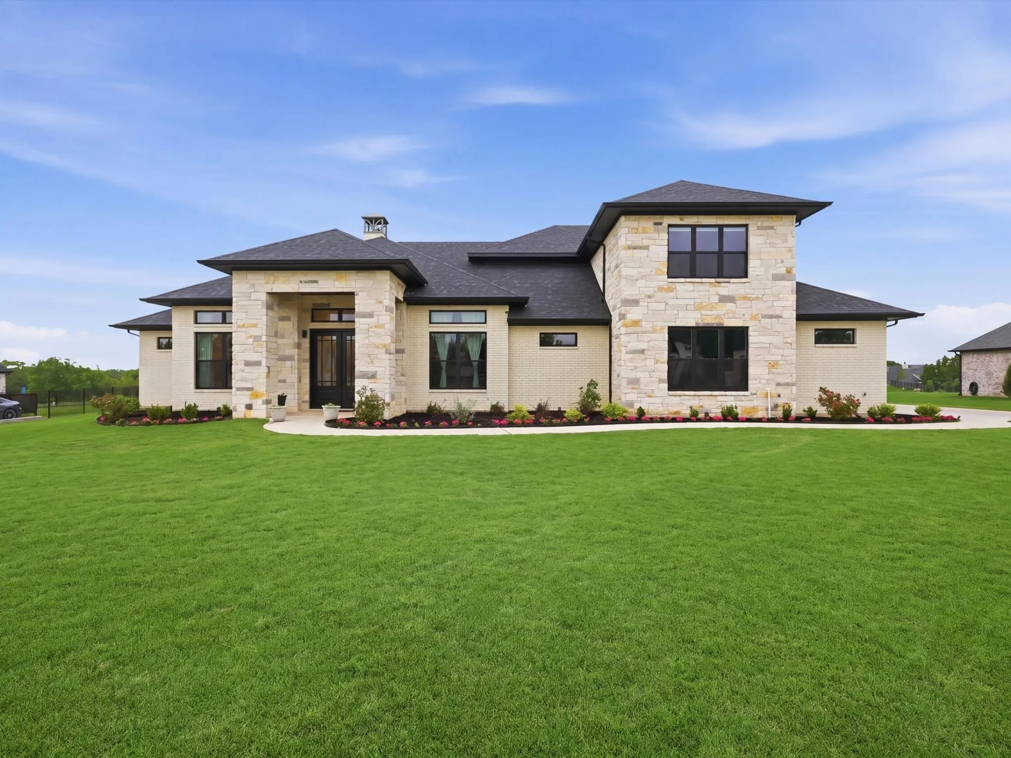 Modern residence featuring a light-colored brick and stone facade with dark framed windows