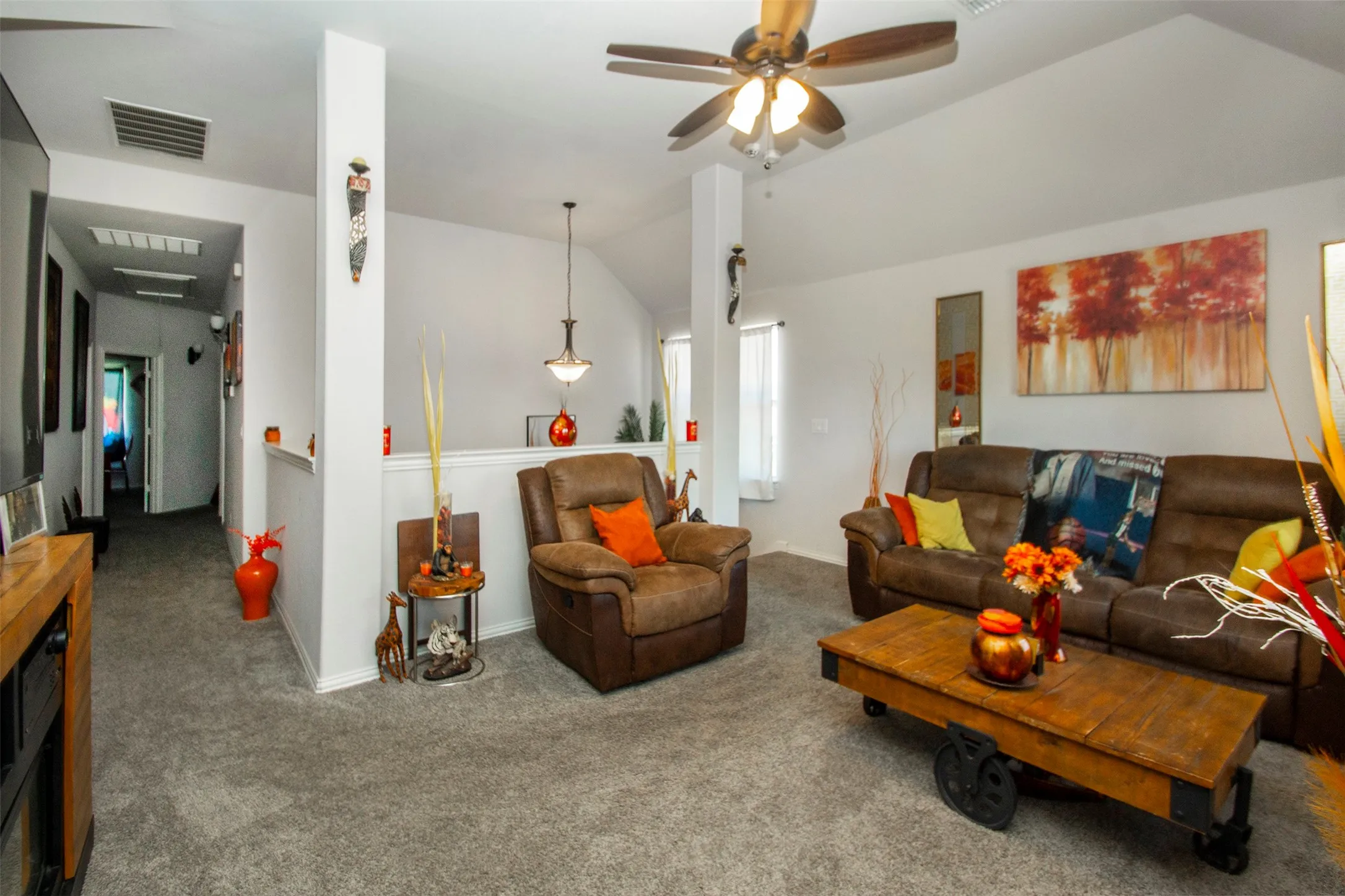 Vaulted ceiling living area featuring light gray carpeting and a ceiling fan with integrated lighting