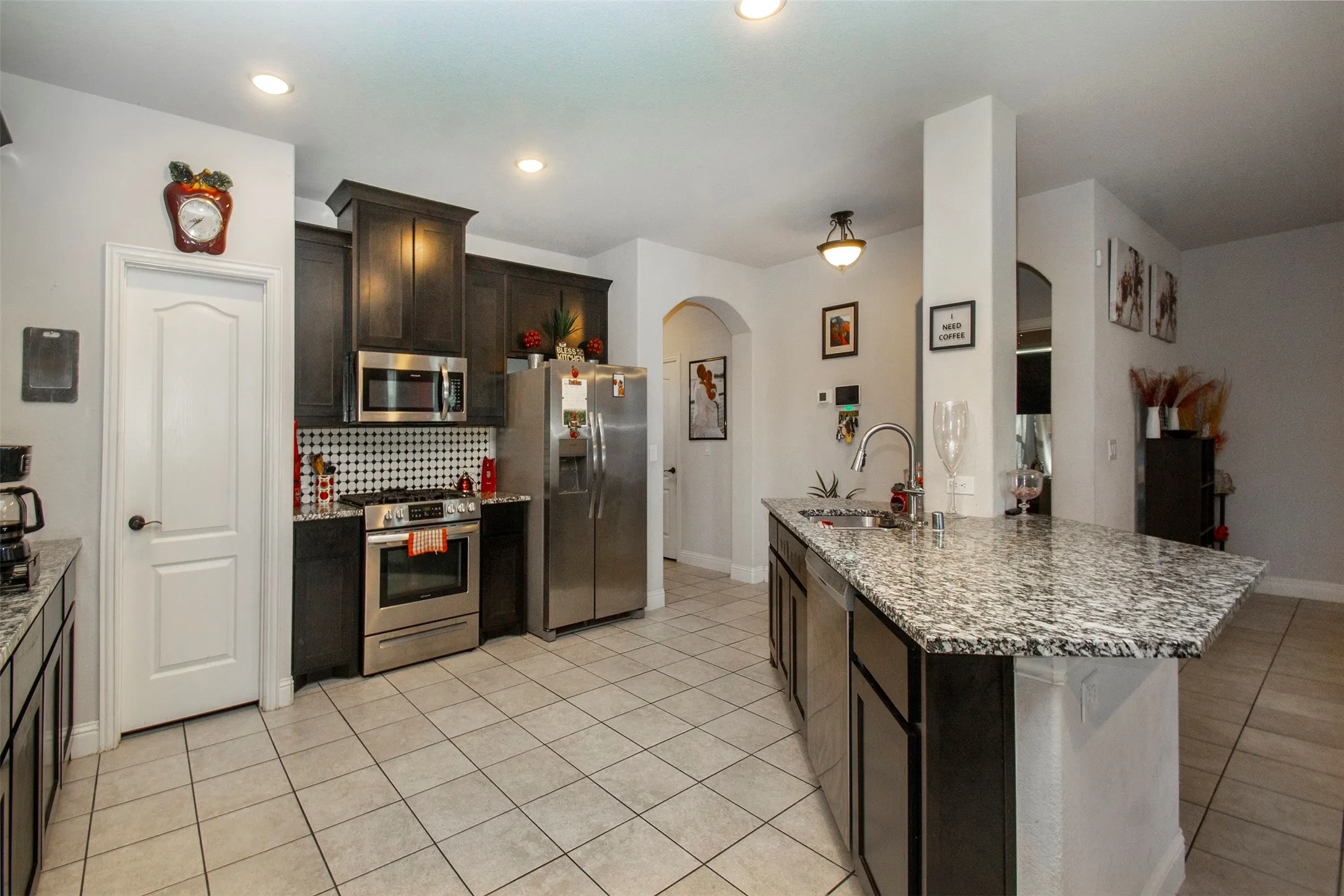 Kitchen featuring an island with stone-finish countertops, dark wood-finish cabinetry, and stainless steel appliances
