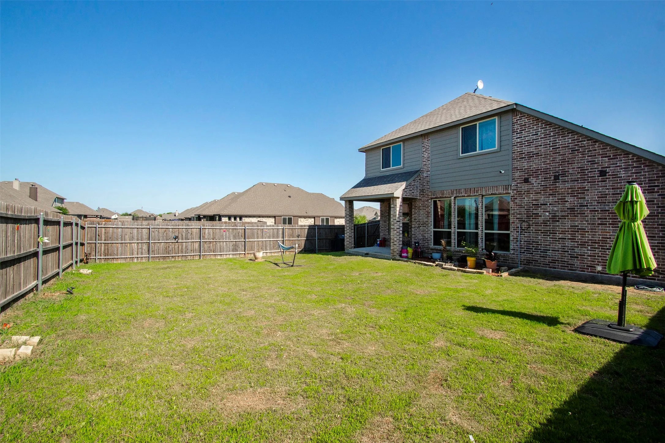 Spacious fenced backyard featuring a two-story residence with brick and siding exterior