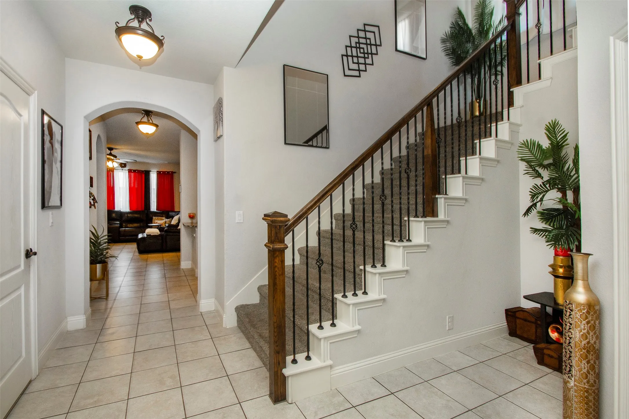 Entryway featuring a carpeted staircase with wrought iron balusters and a dark wood handrail
