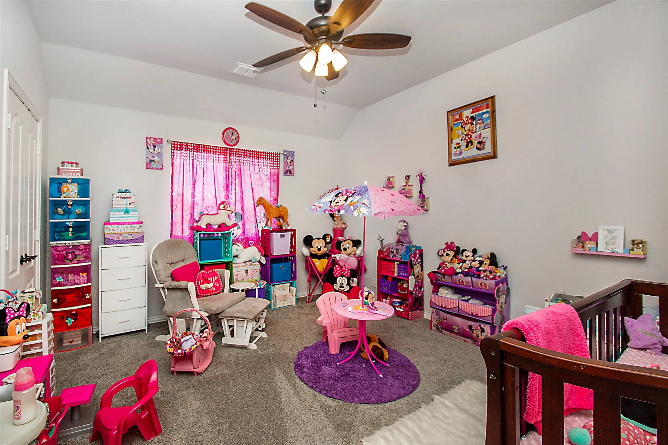 Carpeted room with a ceiling fan light fixture, white walls, and a window featuring pink curtains