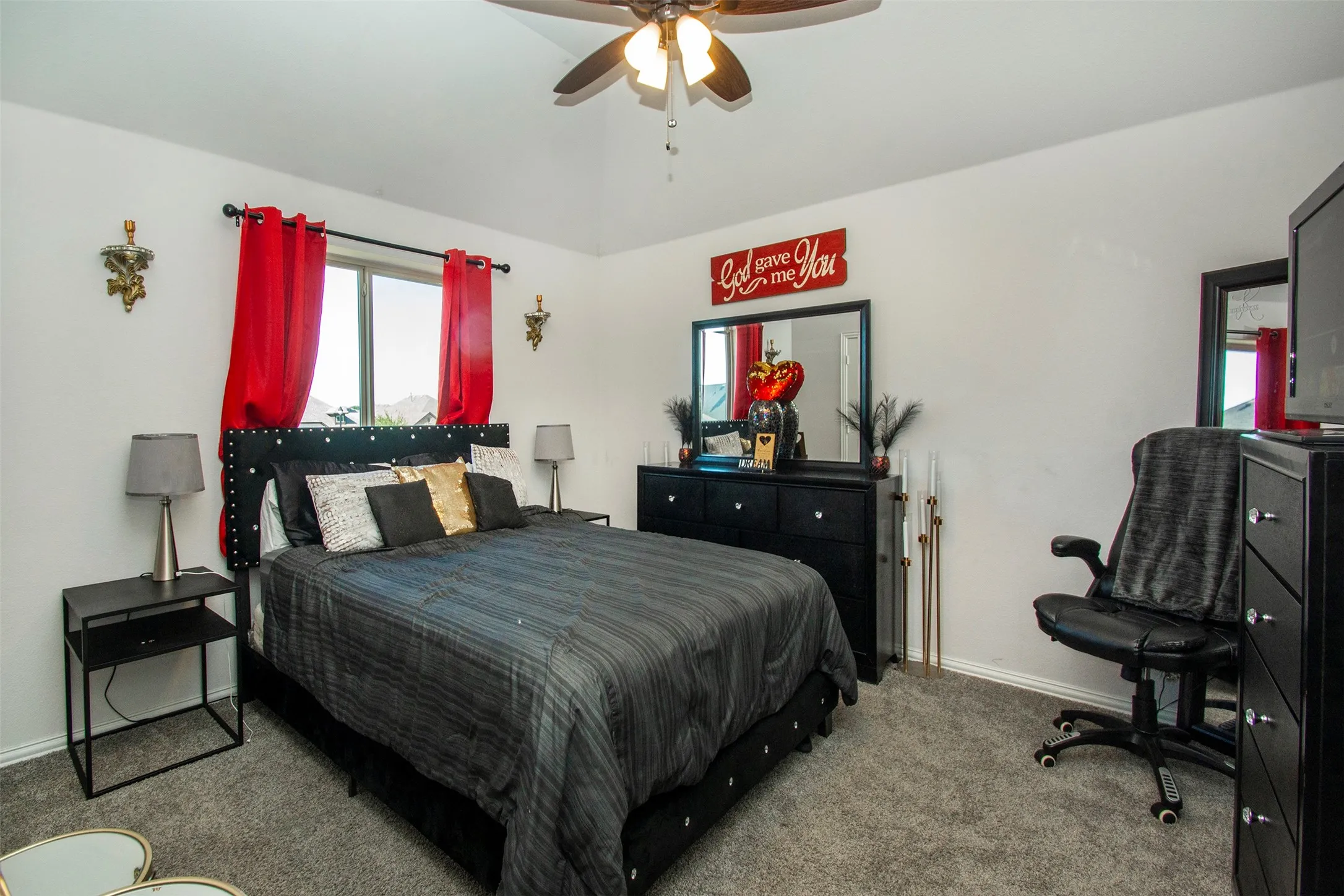 Carpeted room featuring a single window, a ceiling fan, and wall-mounted sconces