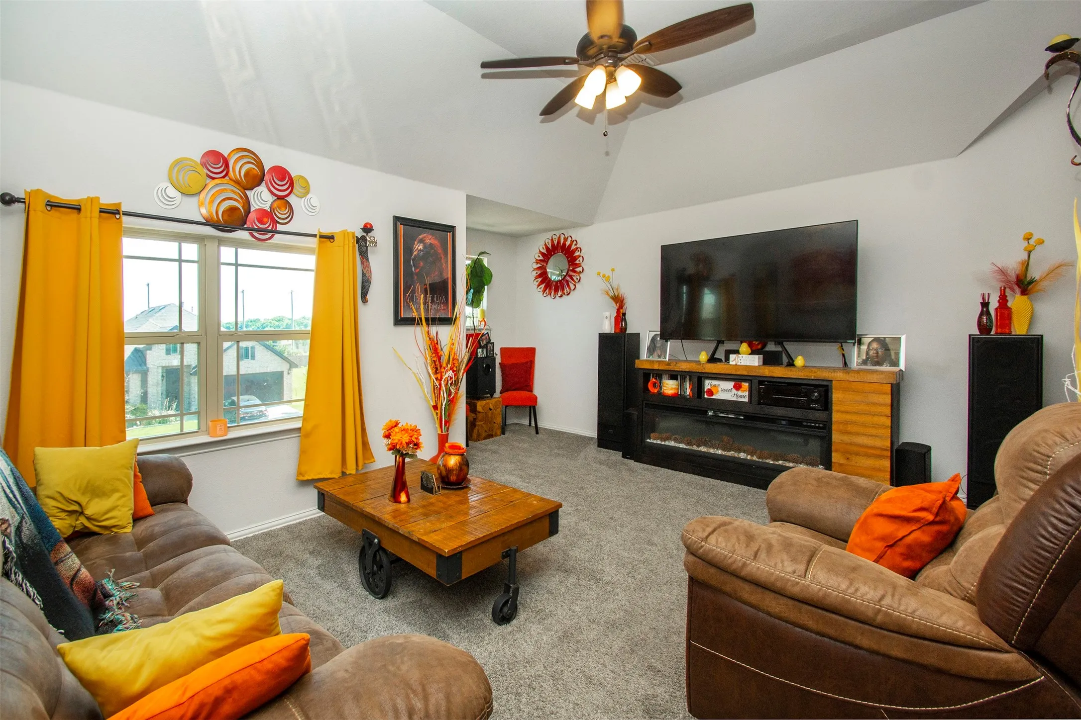 Spacious living area featuring vaulted ceilings, a ceiling fan, and light gray carpeting