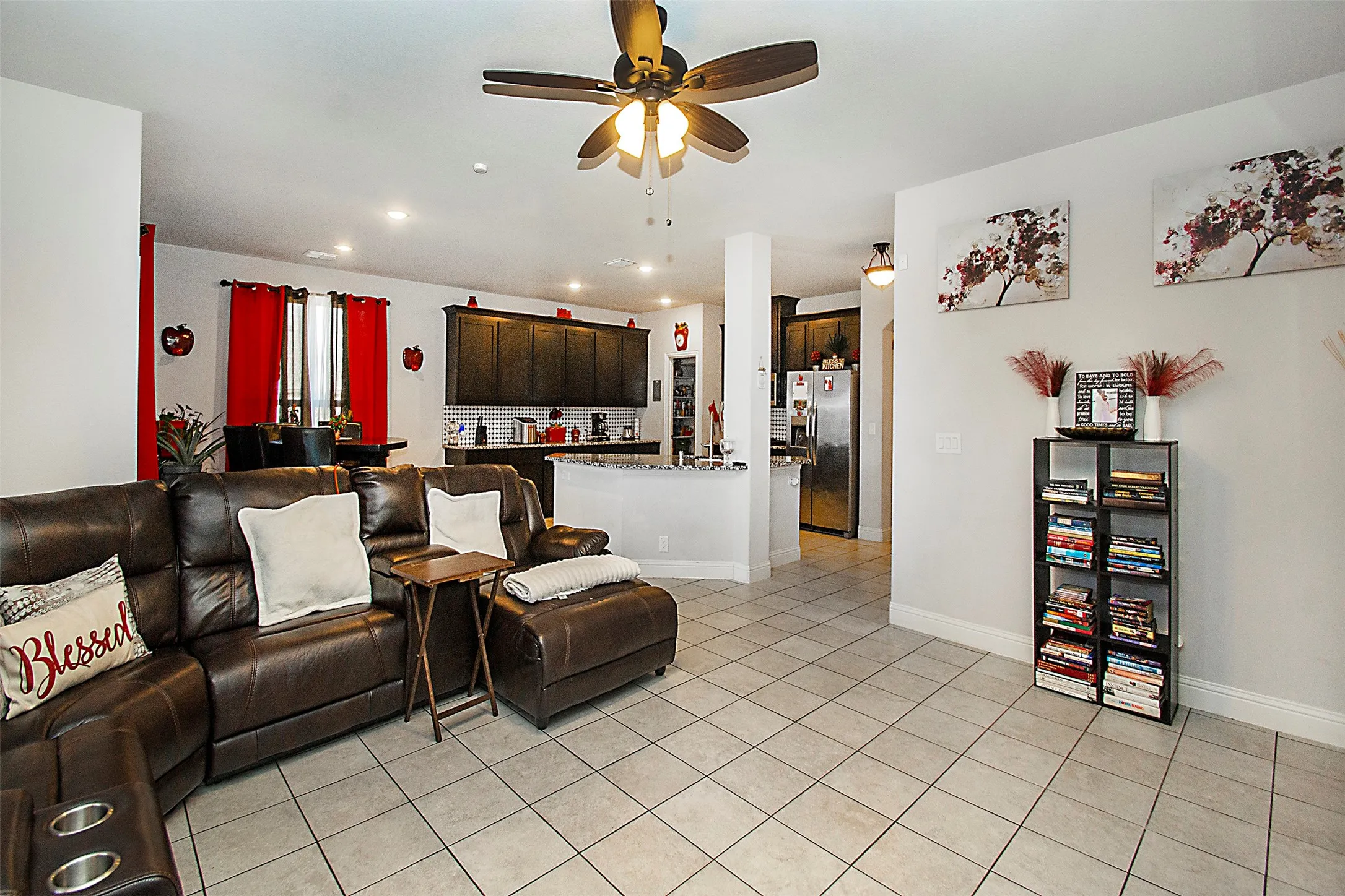 Spacious common area featuring light-toned square tile flooring, a dark-toned ceiling fan with integrated lighting, recessed lighting, and white baseboards