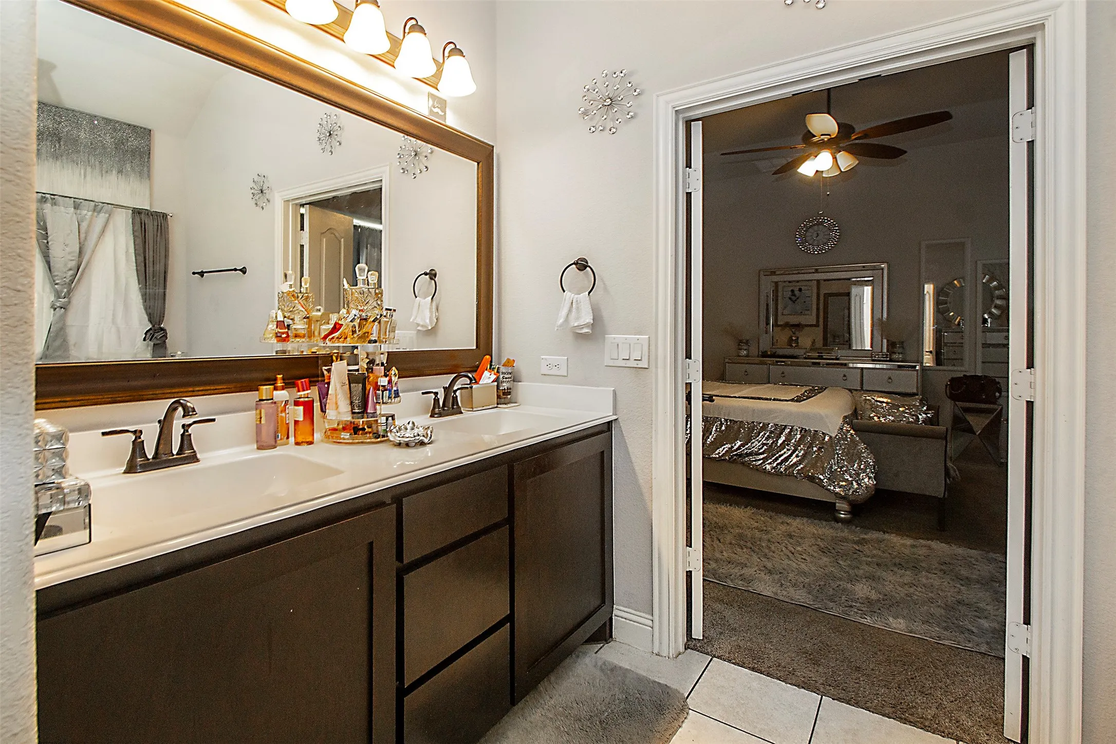 Dual vanity with dark wood-finish cabinetry, white countertops, and bronze-tone fixtures