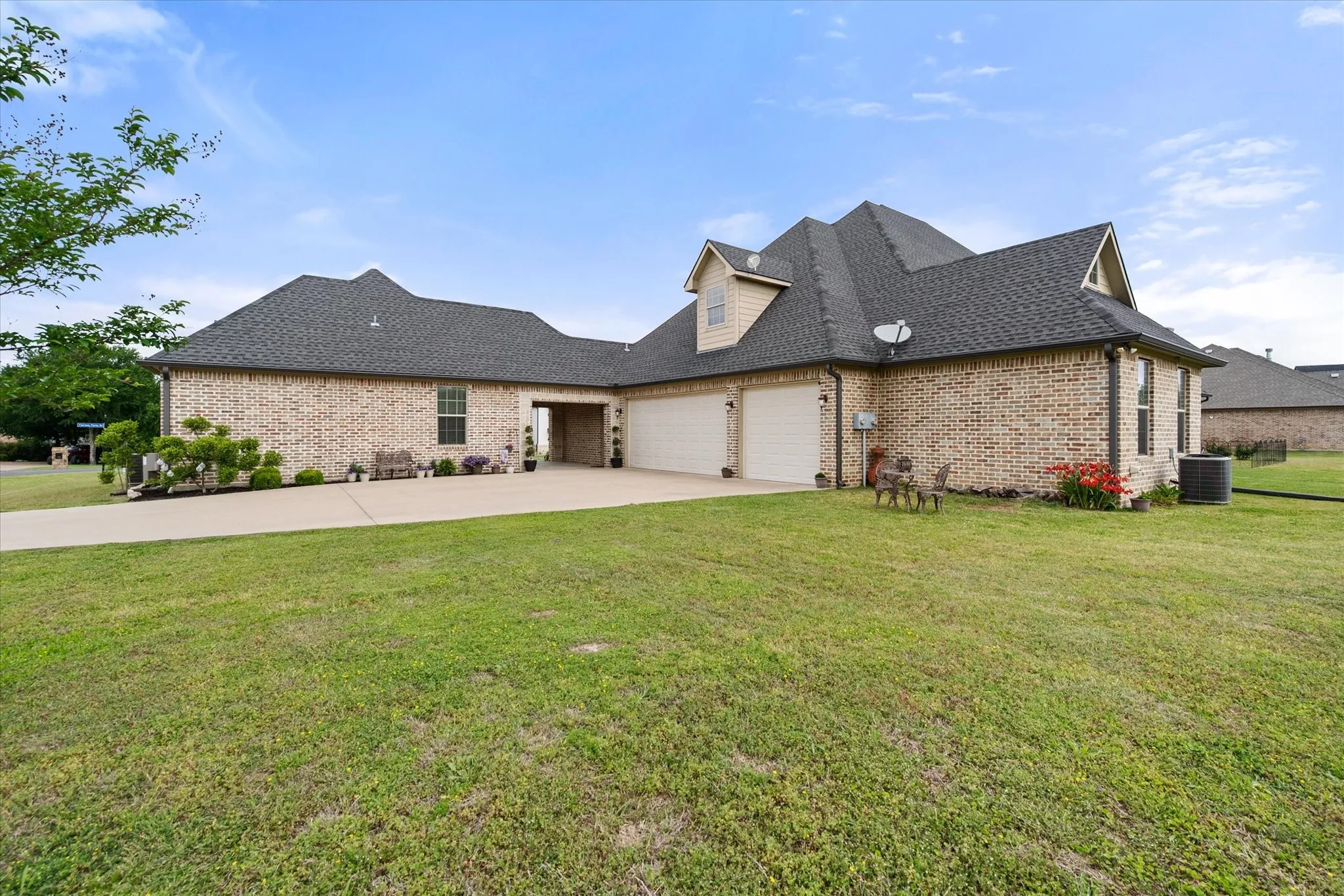 Brick exterior residence featuring a multi-car garage, dormer windows, and a paved driveway