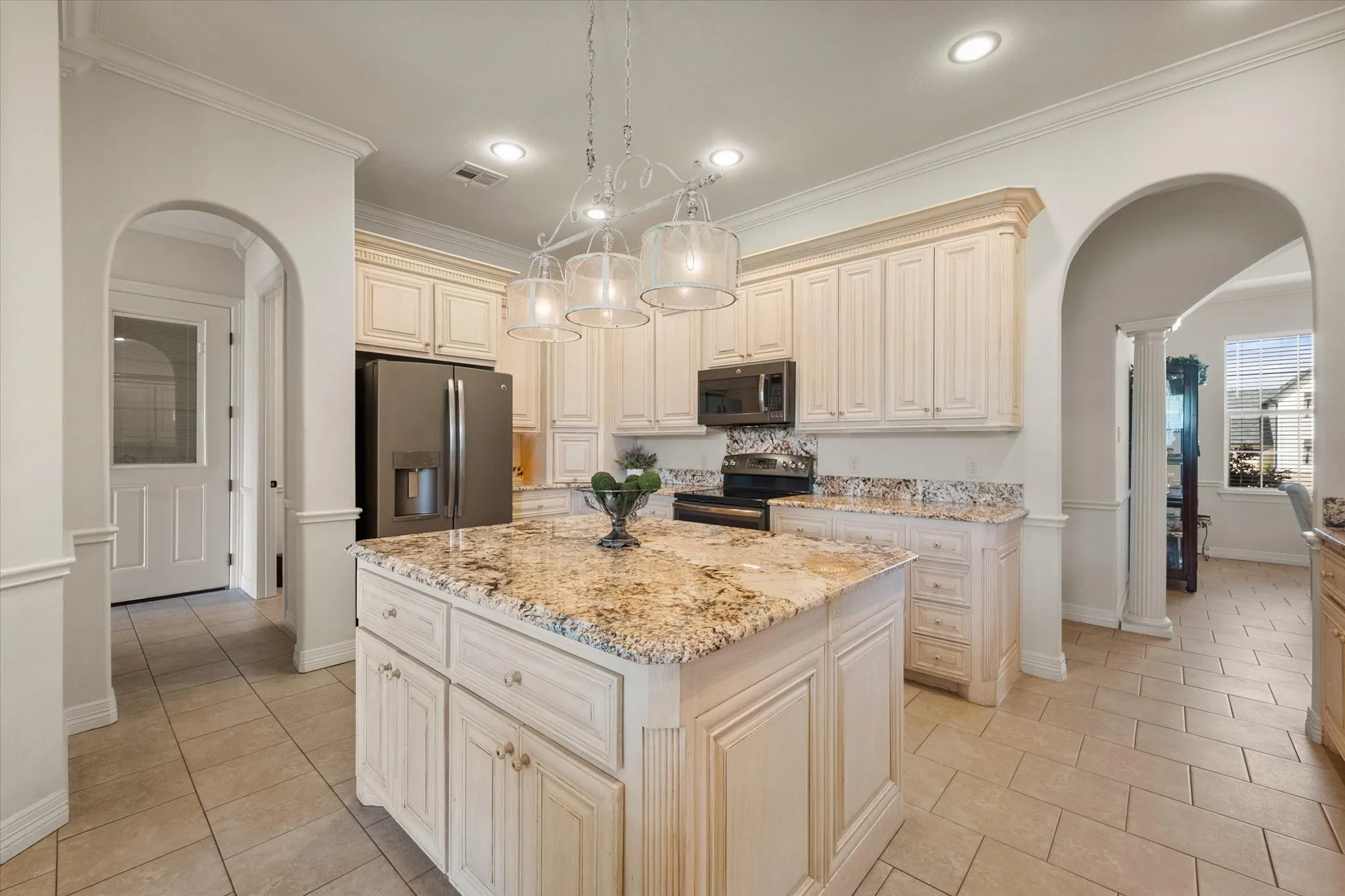 Spacious kitchen featuring a large central island with a stone countertop, extensive cabinetry, a full suite of stainless steel appliances, and recessed lighting
