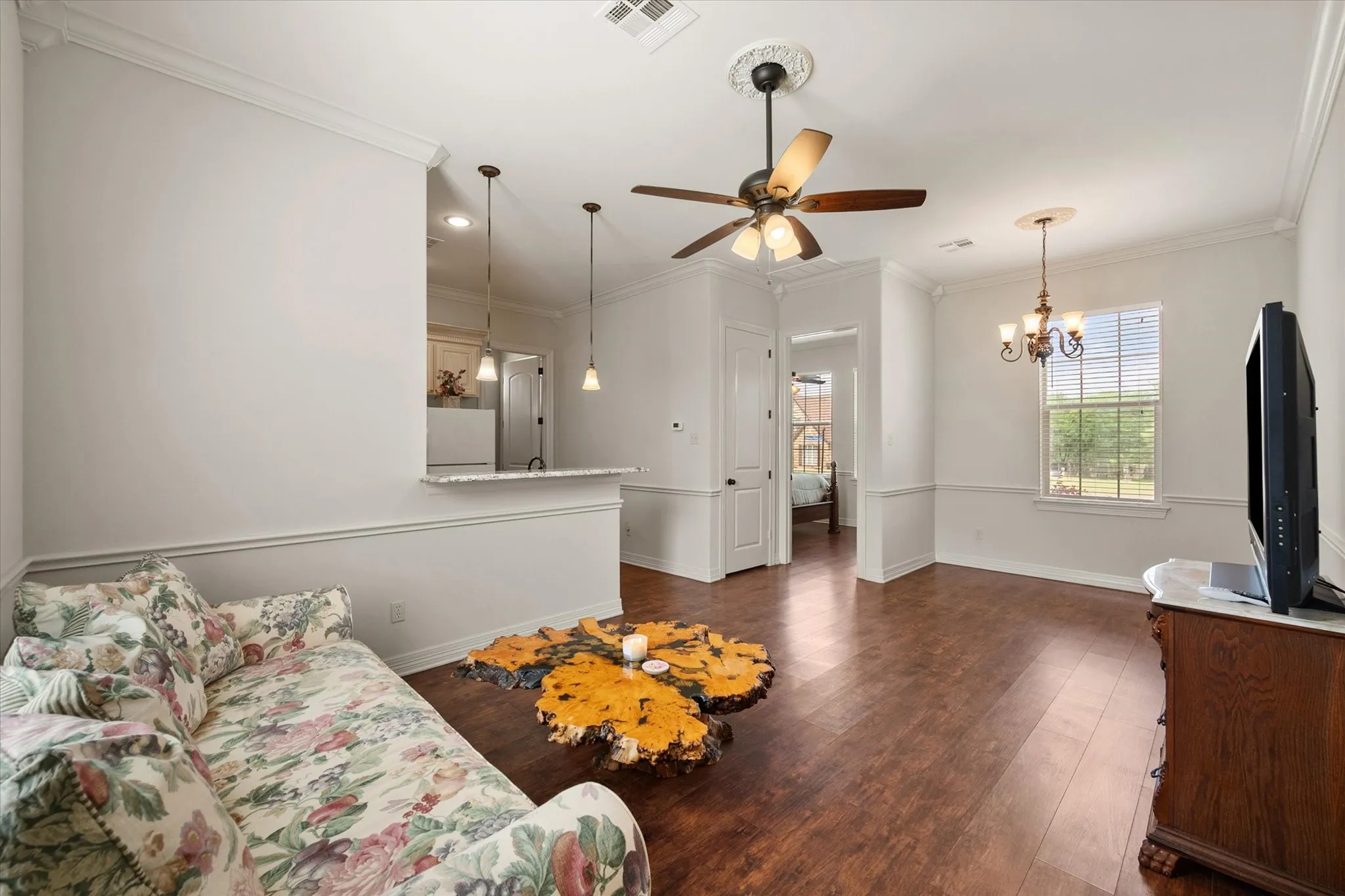 Living, dining combo in the guest apartment with wood-finish flooring, crown molding, and wainscoting