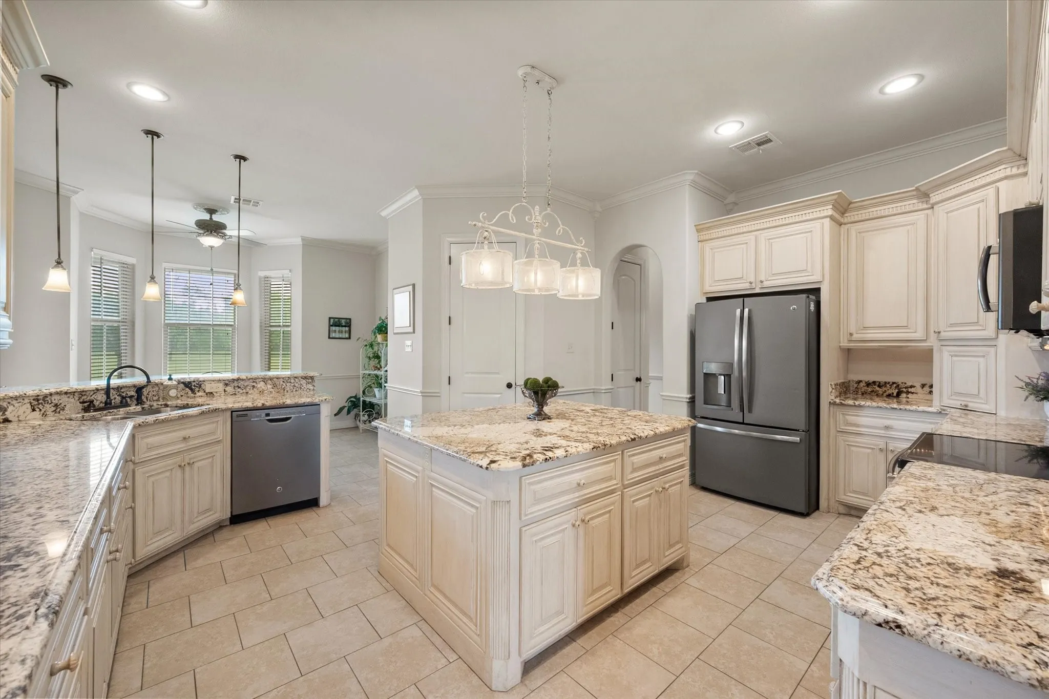 Kitchen featuring light-toned cabinetry, granite countertops, tile flooring, a stainless steel French door refrigerator, and an island with pendant lighting