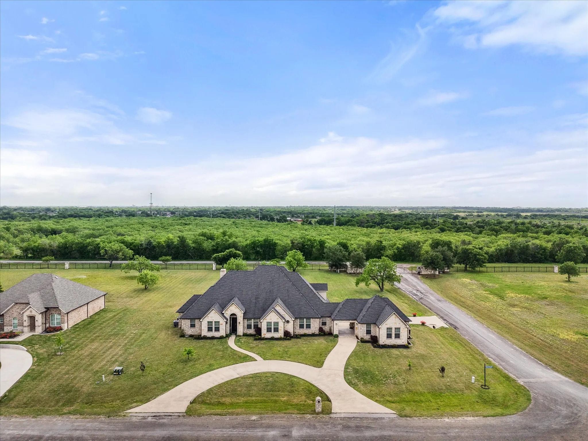 Expansive property featuring a stone and brick exterior, dark shingles, and a curved driveway