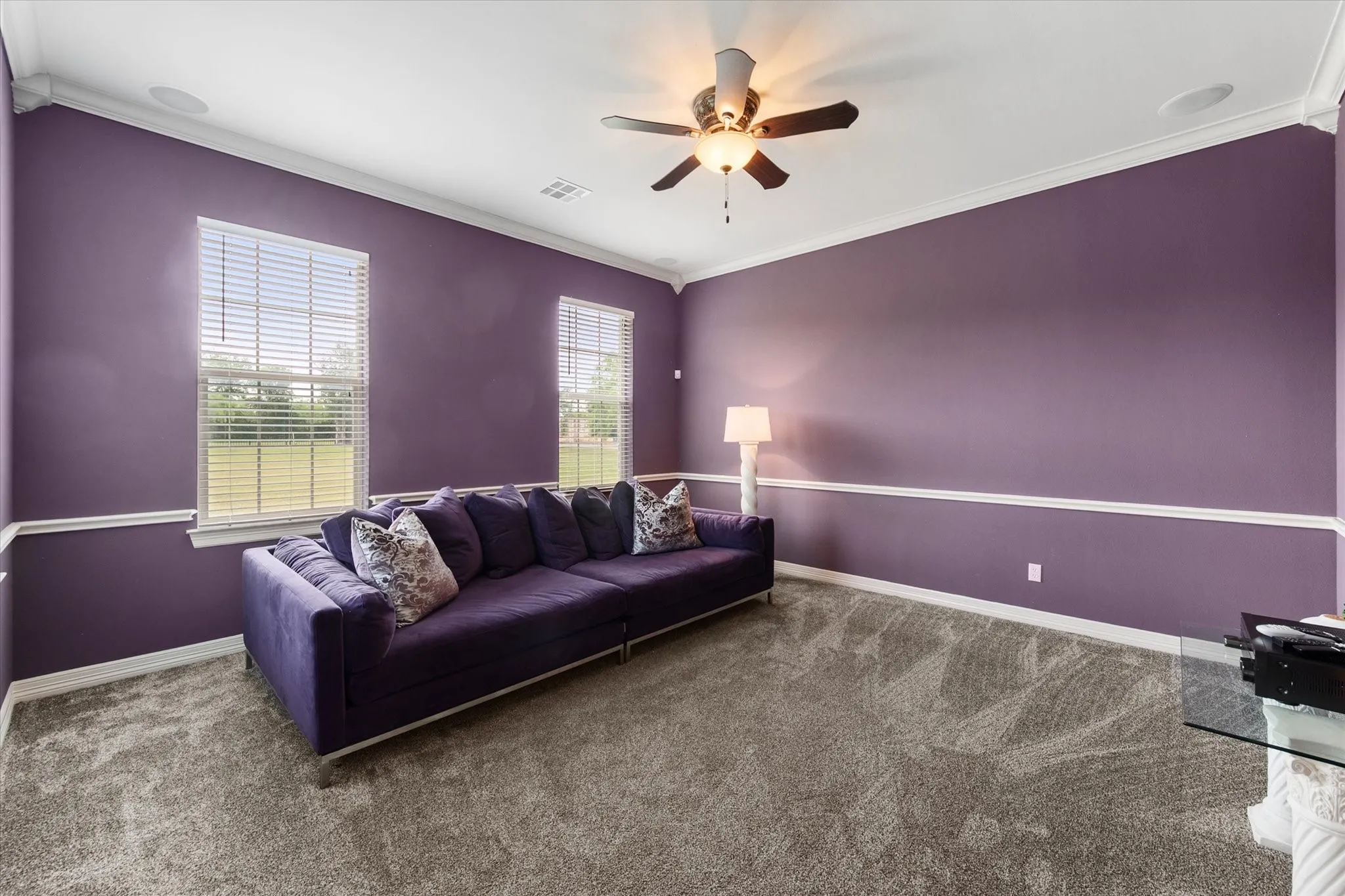 Spacious media room featuring two windows with blinds, a ceiling fan with integrated lighting, recessed lighting, and crown molding